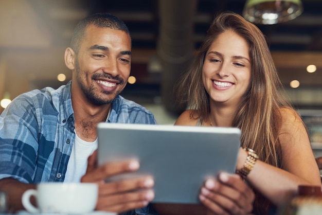 Los clientes obtienen wifi gratis en este café Captura recortada de una pareja joven que usa una tableta digital mientras está sentado en un café