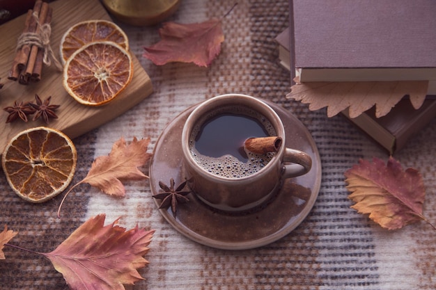 Clima de outono atmosfera de outono Uma xícara de café quente paus de canela anis estrelado um livro folhas de outono em uma manta de malha em um dia chuvoso