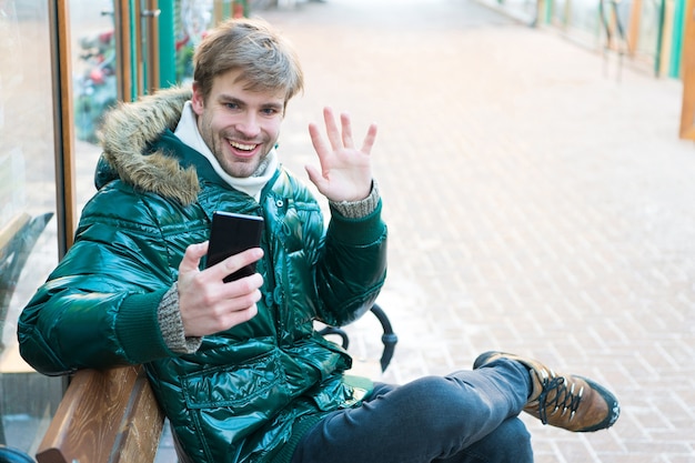 Clima nevado Casaco de inverno na moda Férias viajando Homem feliz nas férias de inverno Homem com telefone