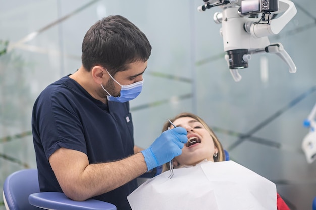 Clínica de odontología moderna con equipo innovador y dentista de tratamiento revisando los dientes de la mujer