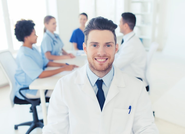 clínica, profissão, pessoas e conceito de medicina - médico masculino feliz sobre um grupo de médicos reunidos no hospital
