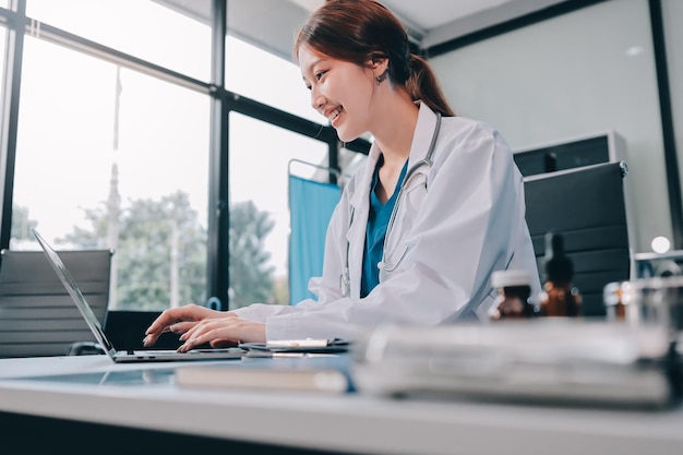 Clínica de salud médica hermosa doctora asiática trabajando usando tableta inteligente tocando estetoscopio diagnosticando paciente análisis investigación examen proveedor de atención médica seguro de servicio en la oficina moderna