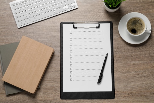 Clipboard mit Kontrollkästen, Tasse Kaffeepflanze und Computer-Tastatur auf einem Holztisch, flach gelegt, Checkliste
