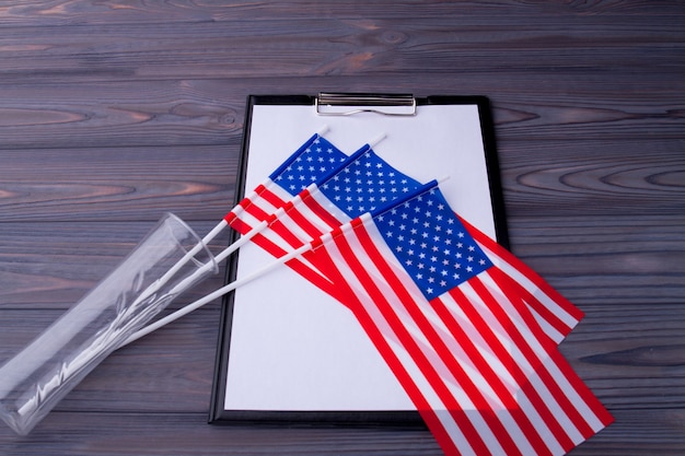 Clipbpard con papel y jarrón de vidrio caído con banderas de EE. UU.