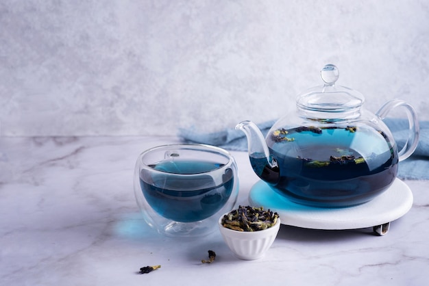 Clitoria ternatea bebe tetera y taza con té anchon azul y flor de guisante de mariposa seca