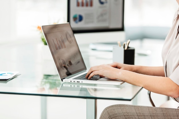 Close - contador trabalhando em um laptop com gráficos financeiros na área de trabalho. a foto tem um espaço vazio para o seu texto.