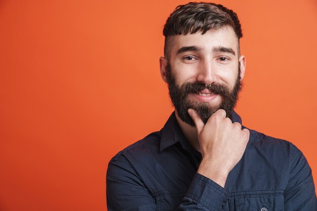 Close da imagem de um homem feliz e elegante com joias no nariz e uma camisa preta sorrindo para a câmera