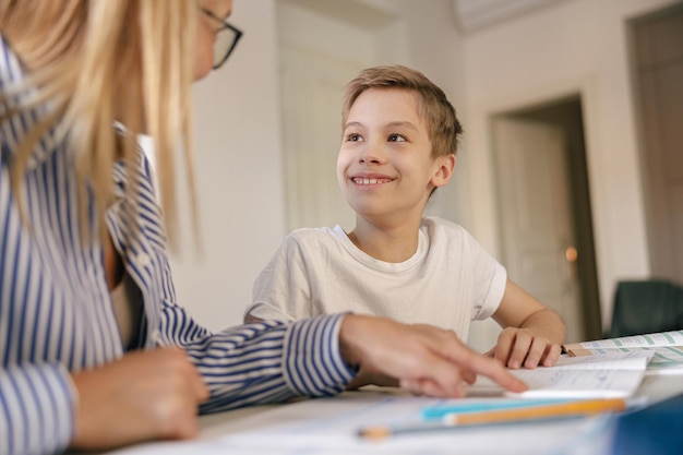 Foto close da mãe ajudando o filho a fazer lição de casa estudando on-line usando laptop em casa