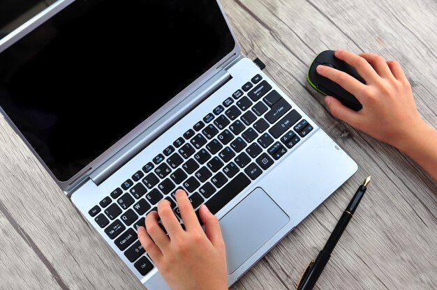 Close da mão de uma mulher de negócios digitando no teclado do laptop com o mouse