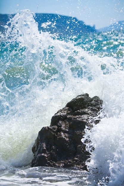 Close da onda do surf do mar quebrando na pedra
