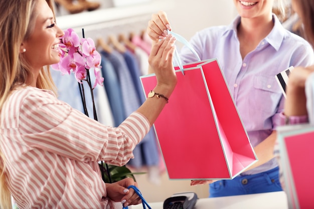 Close da seção intermediária de uma cliente recebendo sacolas de compras na butique