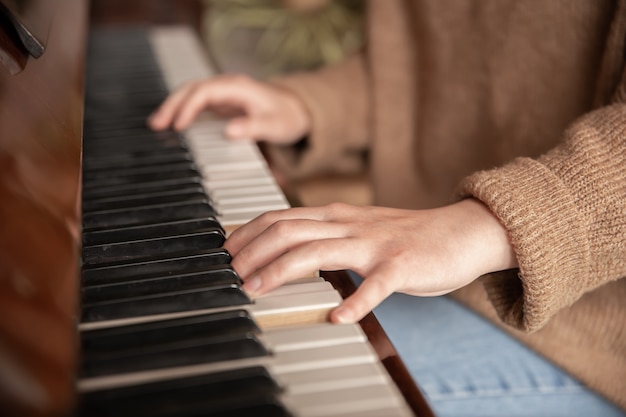 Close das mãos de um pianista nas teclas do piano, mãos femininas tocando piano.