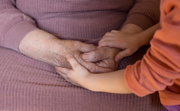 Close das mãos de uma mulher idosa e uma menina. velhice e juventude