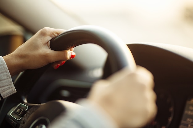 Foto close das mãos de uma mulher no volante, dirigindo com segurança