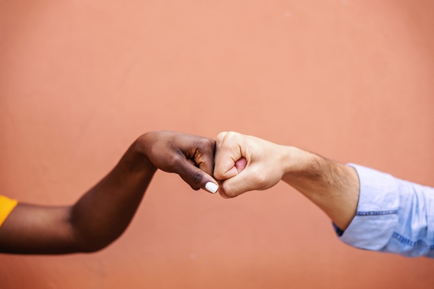 Foto close de amigos multiculturais dando um soco no outro.