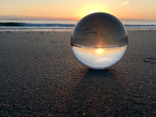 Foto close de bola de cristal na praia durante o pôr do sol