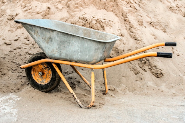 Close de carrinho de mão de construção contra um monte de areia