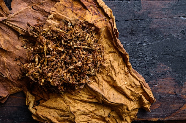 Close de charuto e pilha de tabaco na madeira