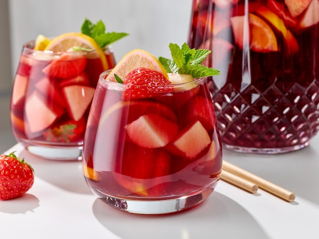 Foto close de copos de sangria vermelhos na mesa da cozinha branca