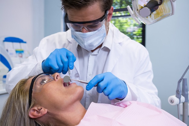 Close de dentista examinando mulher