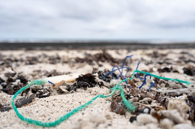 Close de diferentes microplásticos depositados na areia da praia pela ação do ser humano