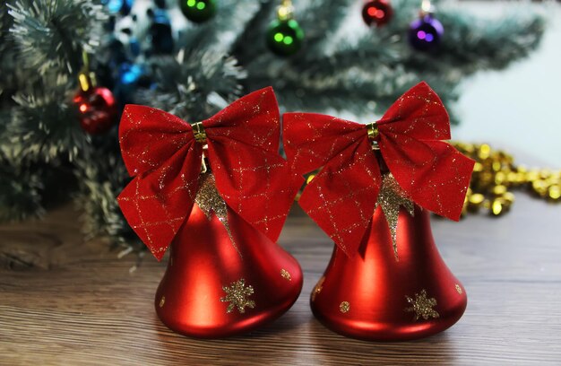 Close de dois lindos sinos vermelhos brilhantes no fundo da árvore de Natal e enfeites no chão de madeira