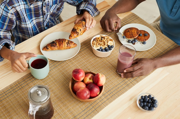 Close de família comendo croissants de panqueca e frutas no café da manhã na mesa de casa