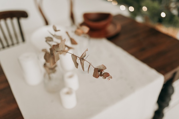 Close de flor artificial em um vaso sobre uma mesa com uma toalha de mesa branca