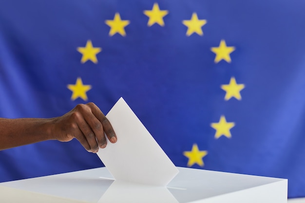 Close de homem africano colocando o envelope na caixa durante a votação