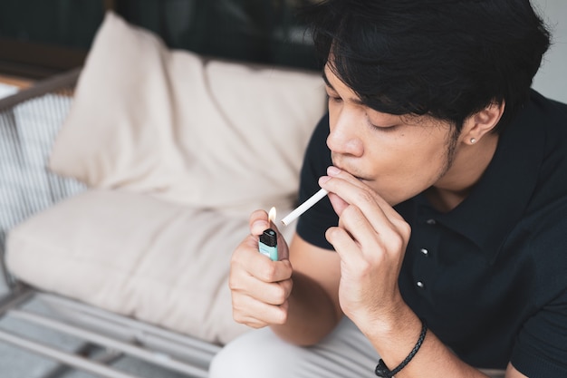 Close de jovem asiático fumando um cigarro