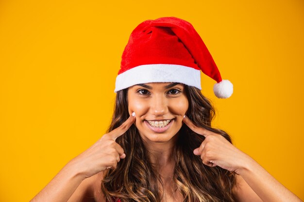 Close de jovem com chapéu de Papai Noel, fazendo caretas.