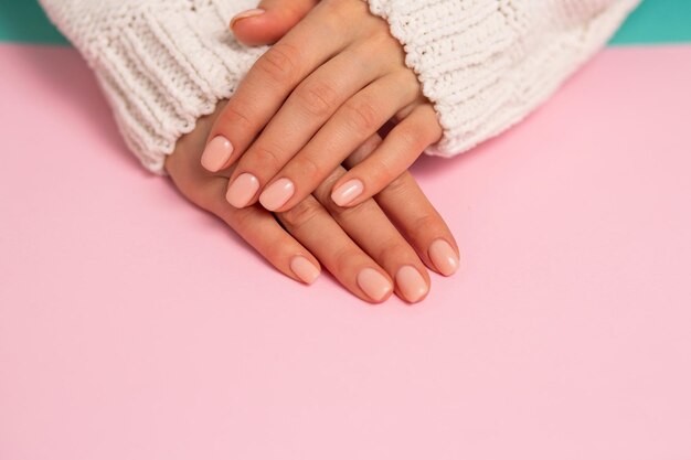 Close de lindas mãos, unhas, manicure delicada em fundo rosa. Cuidado, beleza, Spa, conceito de salão