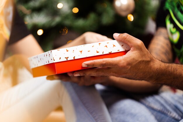 Close de mãos masculinas segurando uma caixa de presente de Natal