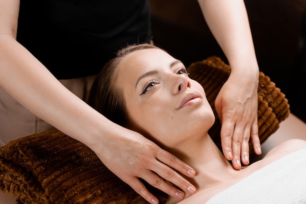 Close de massagem facial no centro de spa. Menina com pele perfeita relaxante na sala de massagem.