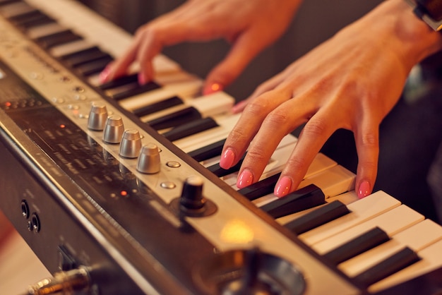 Close de músico tocando teclado de piano elétrico em estúdio