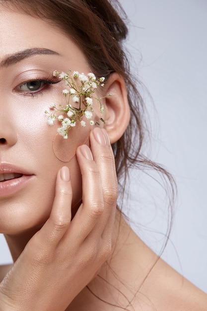 Close de rosto de mulher com linda flor branca e maquiagem nude