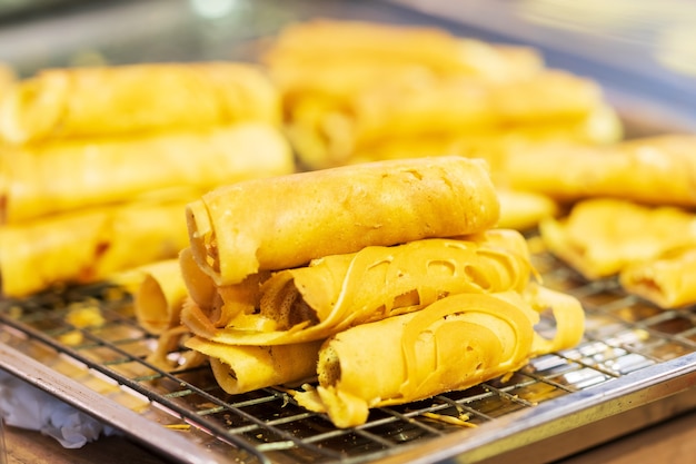 Close de Soft Waffle, Roll pancake recheado, sobremesa tailandesa, mercado de comida de rua tailandesa ao fundo