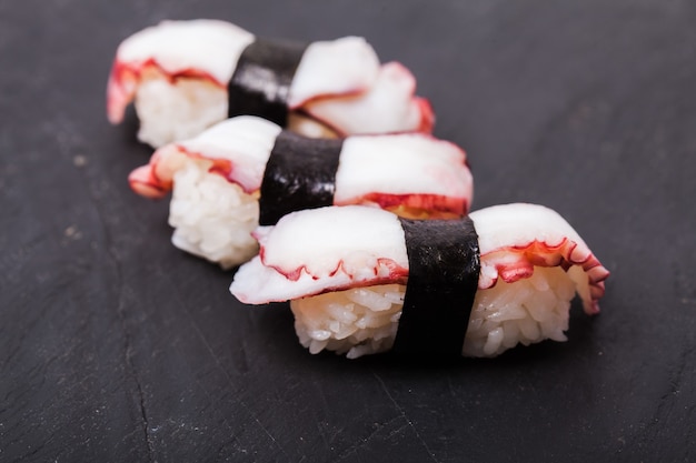 Close de sushi Tako nigiri com polvo cozido em fundo de ardósia preta