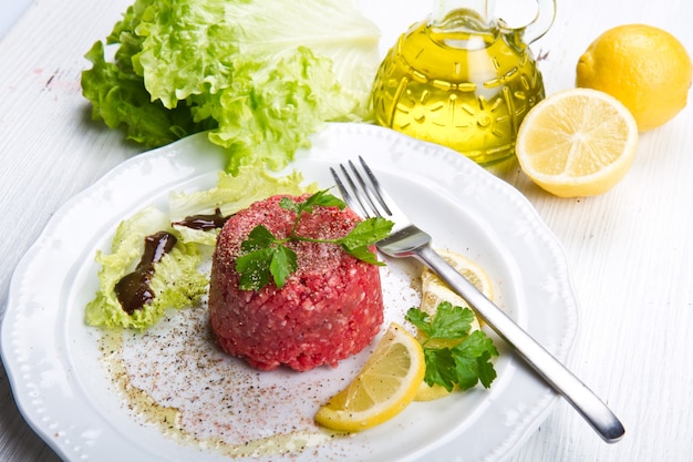 Close de tártaro bovino com salada fresca e rodela de limão