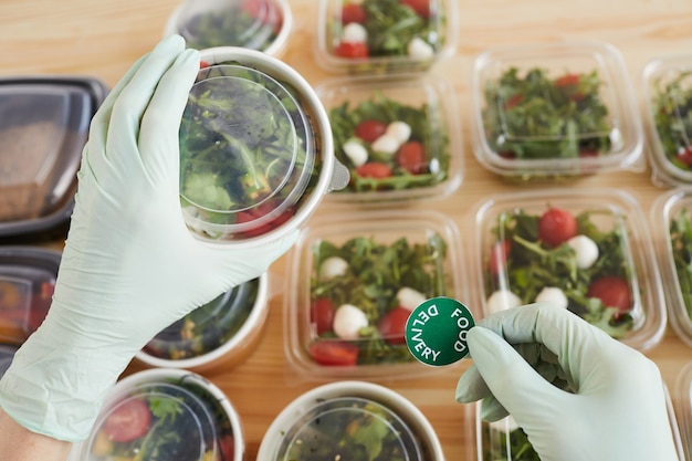 Foto close de trabalhador em luvas de proteção, preparando comida para entrega