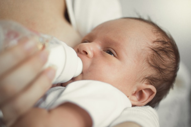 Close de um bebê fofo dormindo nas mãos da mãe depois de comer leite