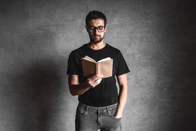 Close de um cara de camiseta preta segurando um livro cinza isolado