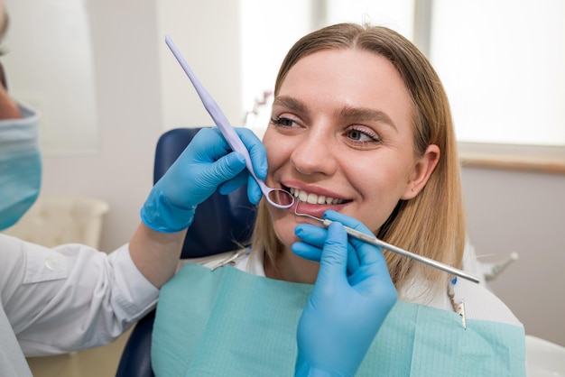 Close de um dentista em uma máscara e um paciente um dentista tratando um paciente loiro jovem alegre sorrindo Odontologia moderna clínica odontológica