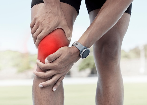 Close de um desportista segurando seu joelho dolorido em vermelho brilhante Atleta desconfortável sofrendo de uma lesão dolorosa na perna e músculos inflamados durante o treino Tensão muscular devido ao esforço excessivo