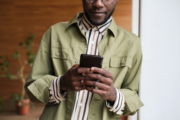 Close de um homem africano digitando uma mensagem no celular e falando online