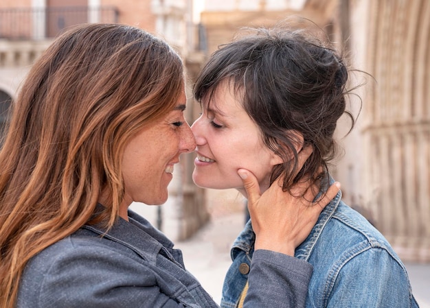 Close de um jovem casal de lésbicas na rua beijando o conceito gay