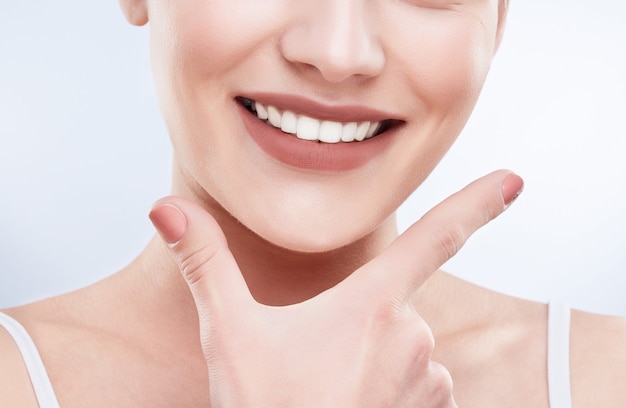 Close de um lindo sorriso branco como a neve. Dentes brancos fortes ideais, cuidados com os dentes. Cuidados de saúde, conceito estomatológico para dentistas. Apenas sorria no rosto, dedos perto do rosto