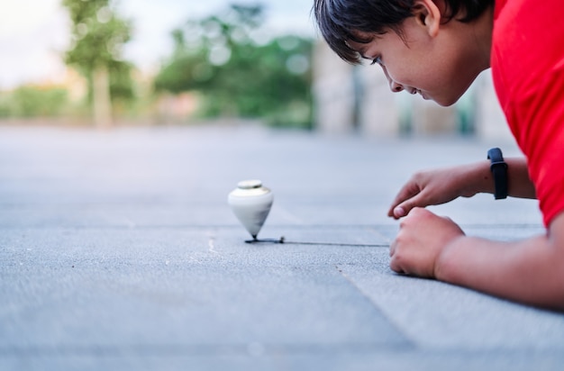 Close de um menino caucasiano brincando com um pião no parque.