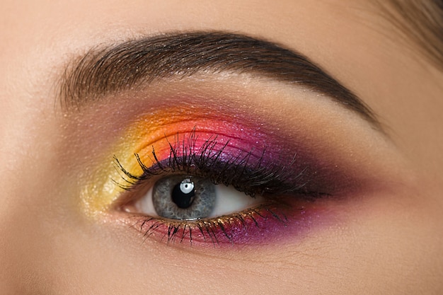 Close de um olho de mulher com uma bela maquiagem colorida