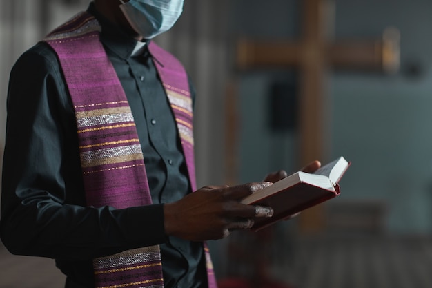 Close de um padre fantasiado lendo a Bíblia enquanto está em frente ao altar durante a cerimônia